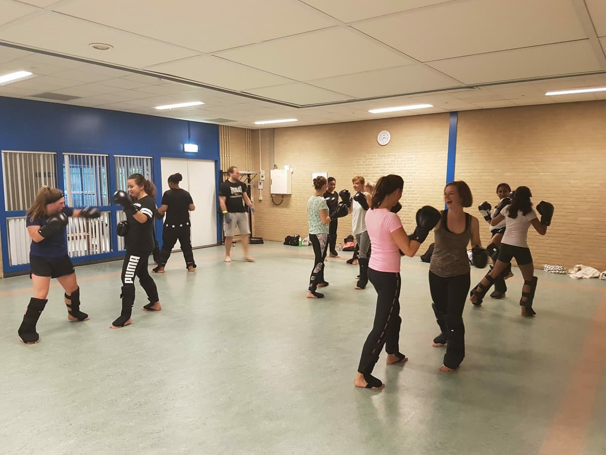 Vrouwen trainen kickboksen met stootkussens in een gymzaal
