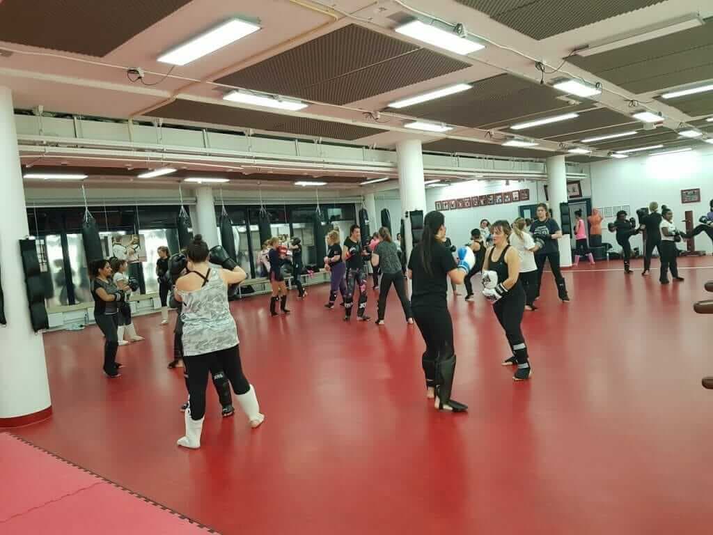 Kickbokstraining voor vrouwen in een grote sportzaal met een rode vloer